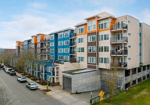 a row of apartment buildings with cars parked on the side of the road